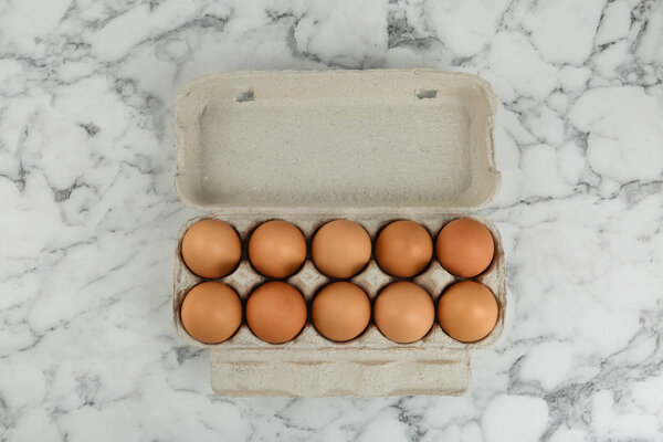 Raw chicken eggs on white marble table, top view