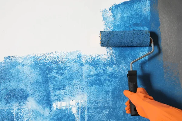 Γυναίκα ζωγραφική λευκό τοίχο με μπλε βαφή, closeup — Φωτογραφία Αρχείου