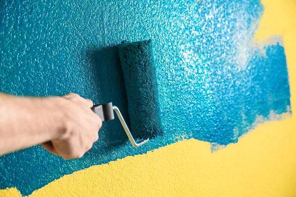 Man painting yellow wall with blue dye, closeup — 스톡 사진