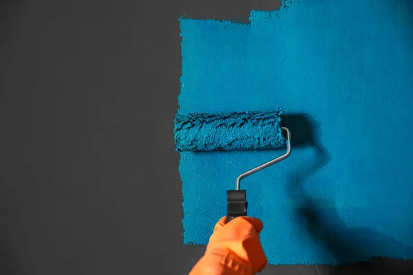 Frau bemalt graue Wand mit blauem Farbstoff, Nahaufnahme — Stockfoto