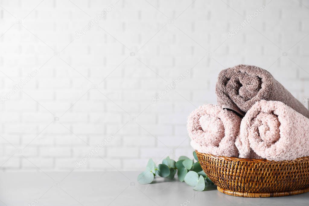 Wicker basket with rolled bath towels and eucalyptus branch near