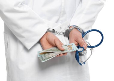 Doktor, rüşvetle kelepçelenmiş ve steteskop takmış.