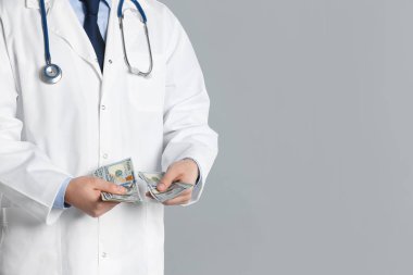 Gri arka planda rüşvet alan doktor, yakın plan. Yatakta yolsuzluk