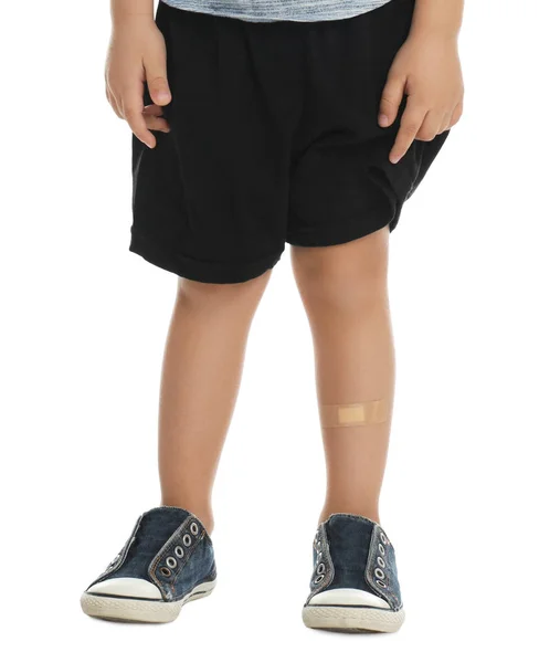 Little boy with sticking plaster on leg against white background — 스톡 사진