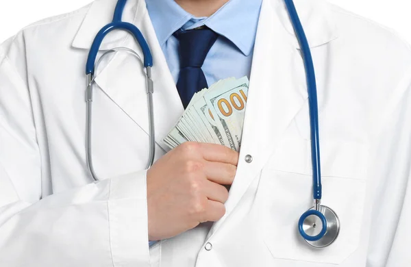 De dokter stopt steekpenningen in zijn zak, close-up. Corruptie in de geneeskunde — Stockfoto