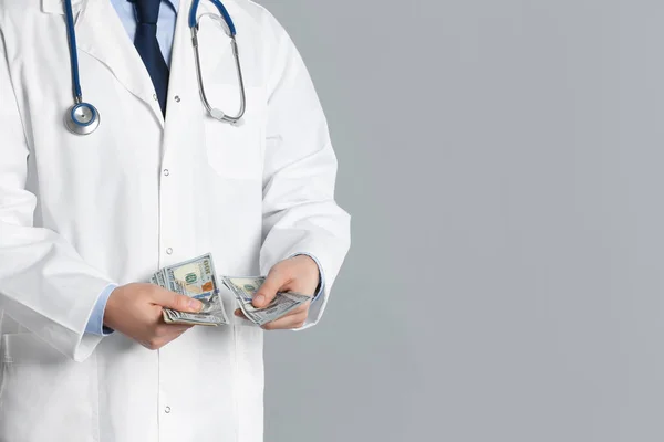 Doctor with bribe on grey background, closeup. Corruption in med — Stock Photo, Image