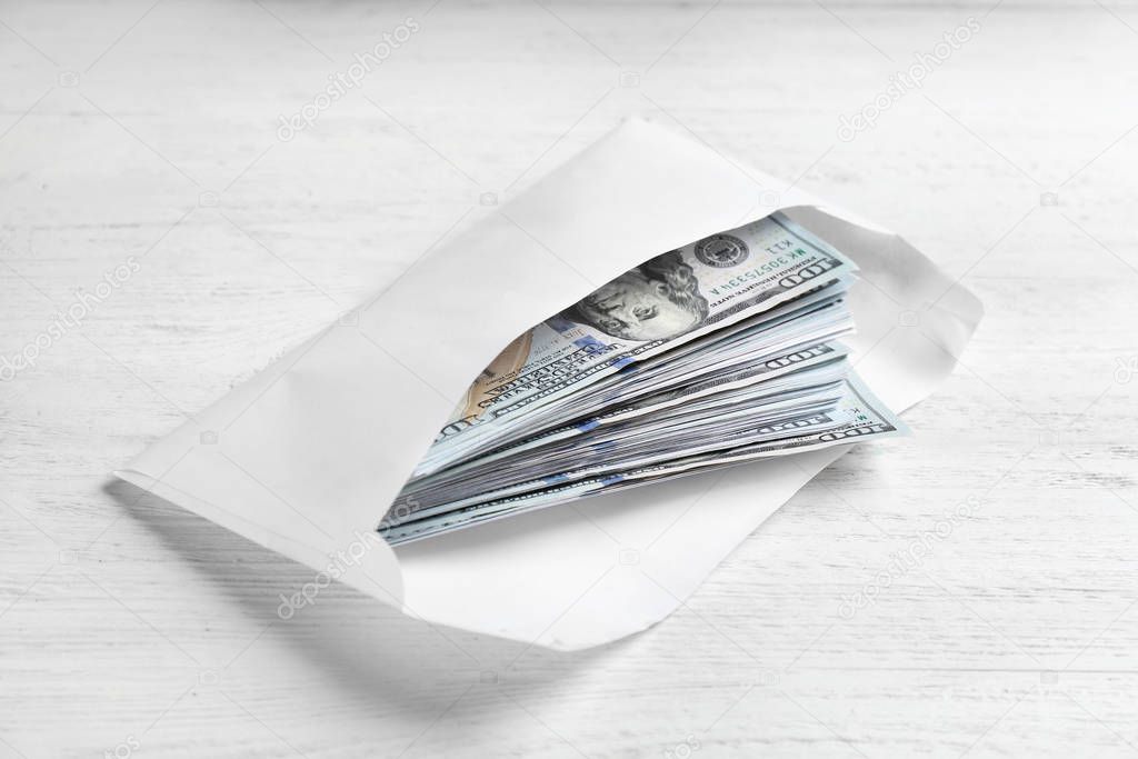 Envelope with dollar bills on white wooden table. Bribe concept