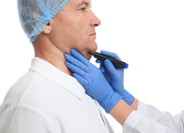 Cirurgião com marcador preparando homem para operação contra ba branca — Fotografia de Stock
