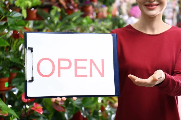 Propietaria de una empresa femenina sosteniendo el cartel OPEN en la floristería, primer plano — Foto de Stock