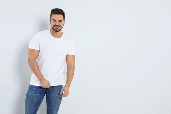 Hombre joven en pantalones vaqueros con estilo sobre fondo claro. Espacio para texto — Foto de Stock