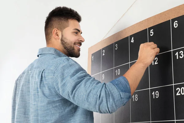 Ung man skriver med krita ombord kalender — Stockfoto