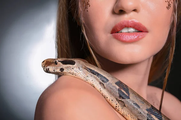 Young woman with boa constrictor on dark background, closeup — Stock Photo, Image