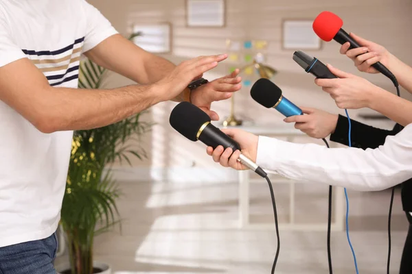 Man avoiding journalist\'s questions at interview indoors, closeup view