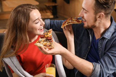 Kafede lezzetli pizzalar yiyen genç çift.