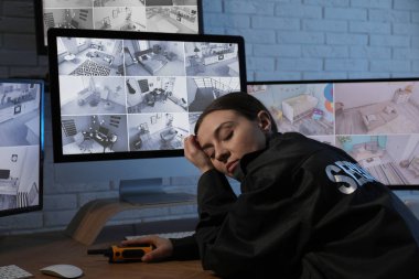 İş yerindeki monitörlerin yanında uyuyan kadın güvenlik görevlisi