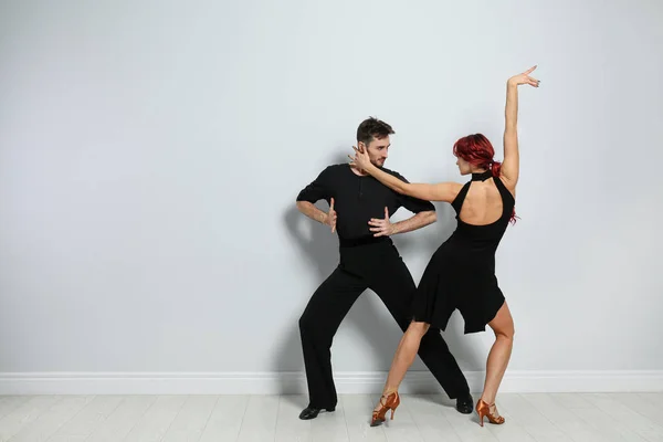 Hermosa pareja joven bailando cerca de la pared de luz. Espacio para texto — Foto de Stock