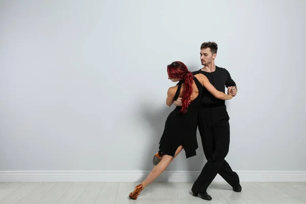 Hermosa pareja joven bailando cerca de pared de luz — Foto de Stock
