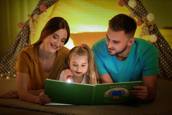 Família com lanterna livro de leitura em casa — Fotografia de Stock