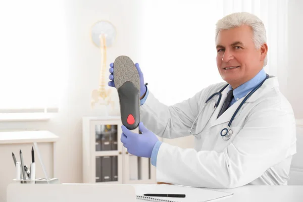 Ortopedista masculino senior mostrando plantilla en clínica — Foto de Stock