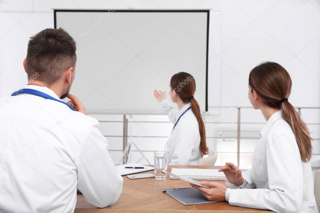 Team of doctors looking at projection screen indoors. 