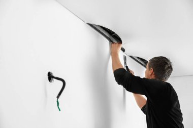 Tamirci odaya beyaz esnek tavan kuruyor.