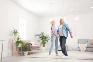 Mutlu olgun çift oturma odasında dans ediyor.