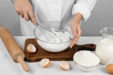 Ahşap masada yumurta beyazı çırpan kadın, yakın plan. Pasta yapmak.