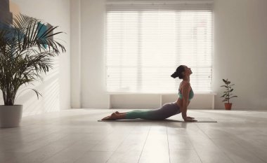 Yoga stüdyosunda kobra asana pratiği yapan bir kadın. Bhujangasana pozu