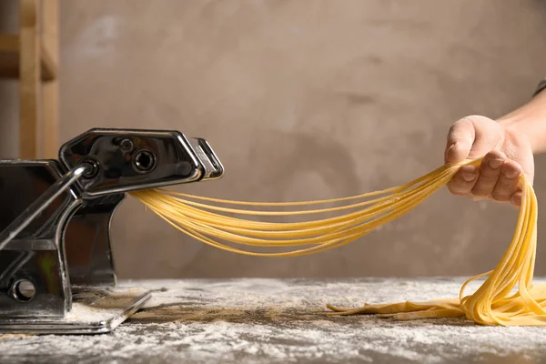 Vrouw bereidt noedels met pasta maker machine aan tafel, sluiten — Stockfoto