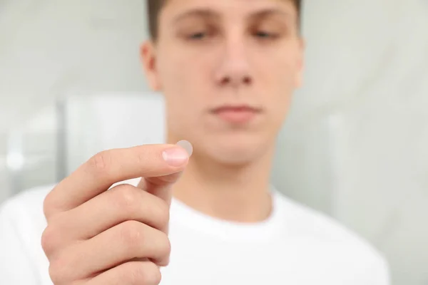 Teen guy using acne healing patch indoors, focus on hand — 스톡 사진