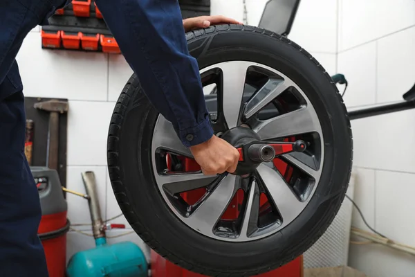 Homem trabalhando com máquina de balanceamento de rodas ao serviço de pneus, closeu — Fotografia de Stock
