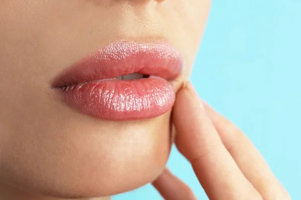 Frau mit schönen vollen Lippen auf hellblauem Hintergrund, Nahaufnahme — Stockfoto