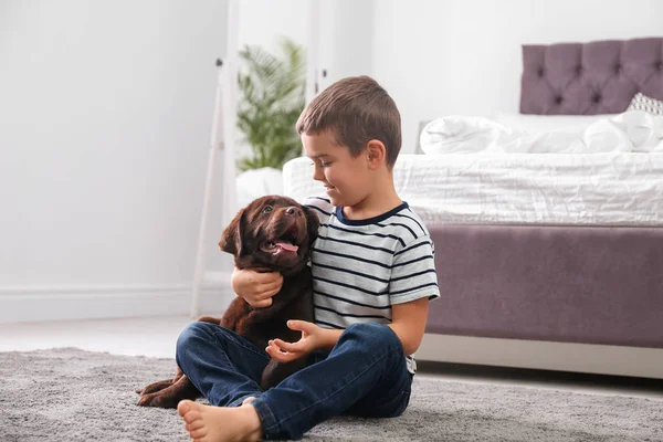 Маленький хлопчик з цуценям на підлозі у спальні. Дружній собака — стокове фото