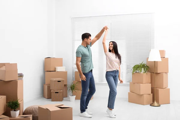 Happy couple dancing in room with cardboard boxes on moving day — 스톡 사진