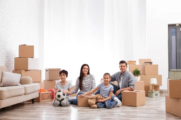 Happy family in room with cardboard boxes on moving day — Stock Photo, Image