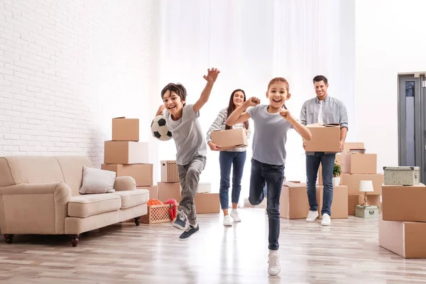 Familia feliz en la habitación con cajas de cartón en el día en movimiento —  Fotos de Stock