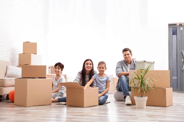 Happy family unpacking moving boxes at their new home — Stock Photo, Image