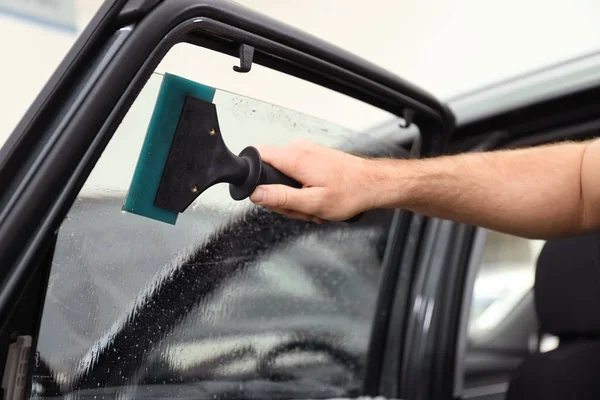 Worker washing tinted car window in workshop, closeup — Stock Photo, Image