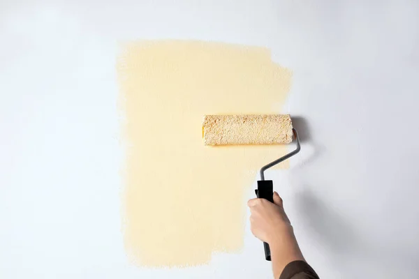 Mujer pintando pared blanca con tinte beige, primer plano — Foto de Stock