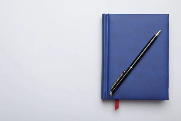 Elegante cuaderno azul y pluma sobre fondo gris claro, vista superior —  Fotos de Stock
