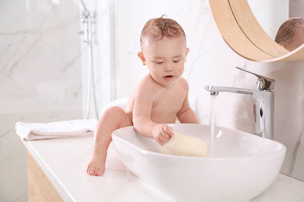 Cute little baby playing in bathroom at home
