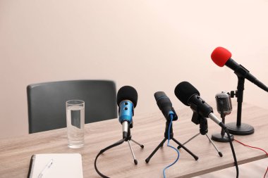 Journalist's microphones on wooden table in room clipart
