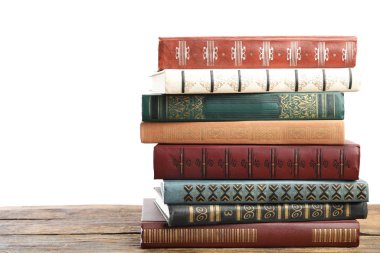 Beyaz arkaplana karşı ahşap masa üzerinde eski antika kitap yığını