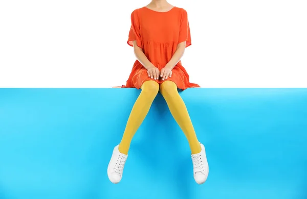 Mujer con medias amarillas y zapatos elegantes sentado en el color b —  Fotos de Stock