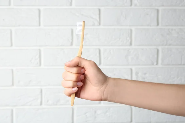 Mulher Segurando Escova Dentes Bambu Contra Parede Tijolo Branco Close — Fotografia de Stock