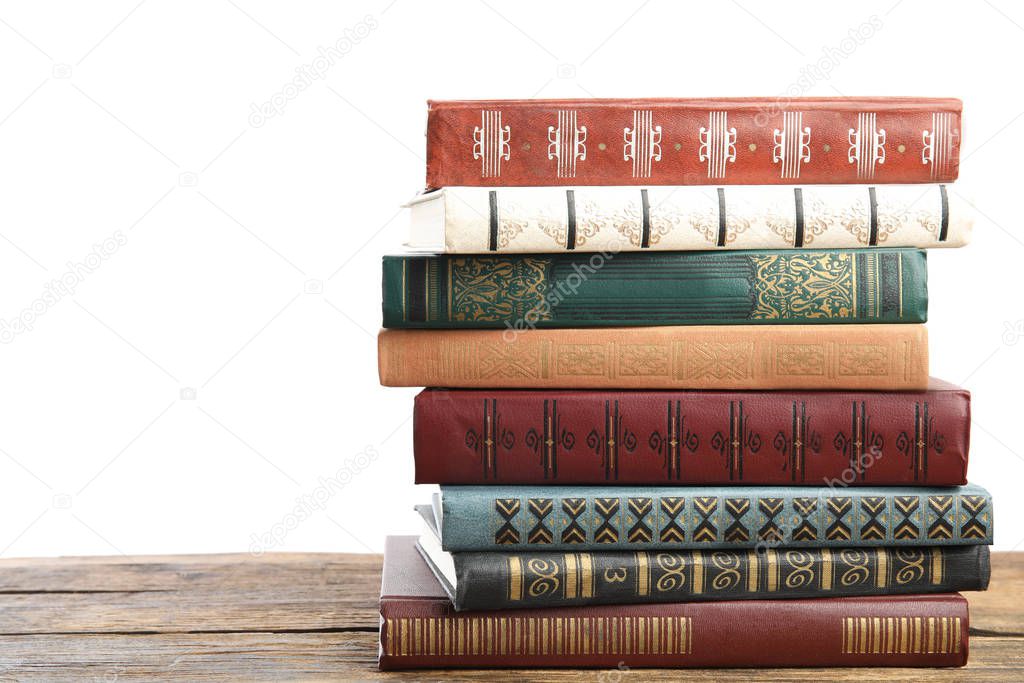 Stack of old vintage books on wooden table against white background