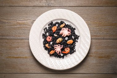 Ahşap masa üzerinde deniz mahsulleri olan leziz siyah risotto.