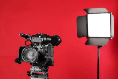 Kırmızı arkaplanda profesyonel video kamera ve ışıklandırma ekipmanları