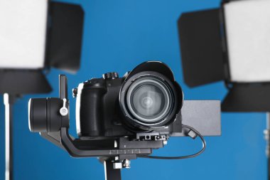 Mavi arka planda profesyonel video kamera ve ışıklandırma ekipmanları