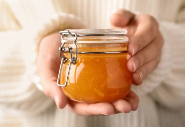 Woman with jar of orange jam, closeup clipart